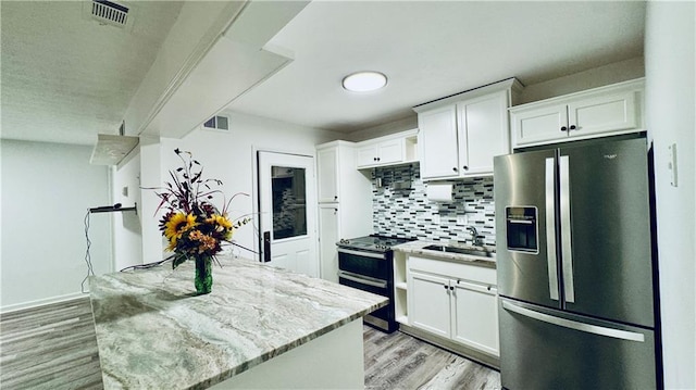 kitchen with white cabinetry, sink, light stone counters, and appliances with stainless steel finishes