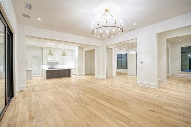 unfurnished living room featuring light wood-type flooring and a chandelier