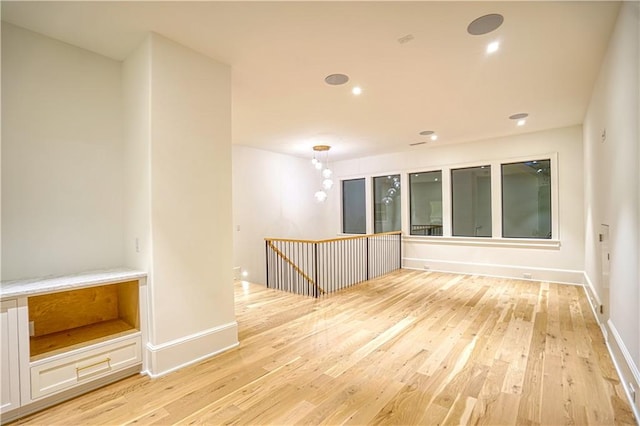 empty room featuring light hardwood / wood-style flooring and a notable chandelier