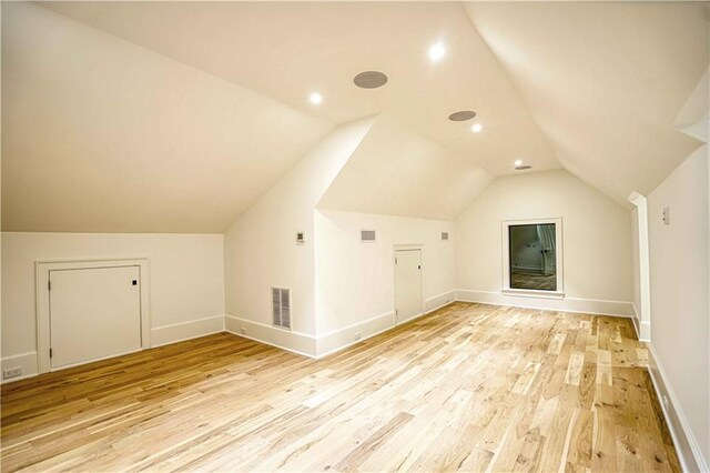 additional living space with light wood-type flooring and vaulted ceiling