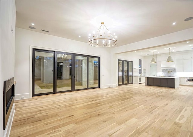 unfurnished living room featuring light hardwood / wood-style flooring and an inviting chandelier