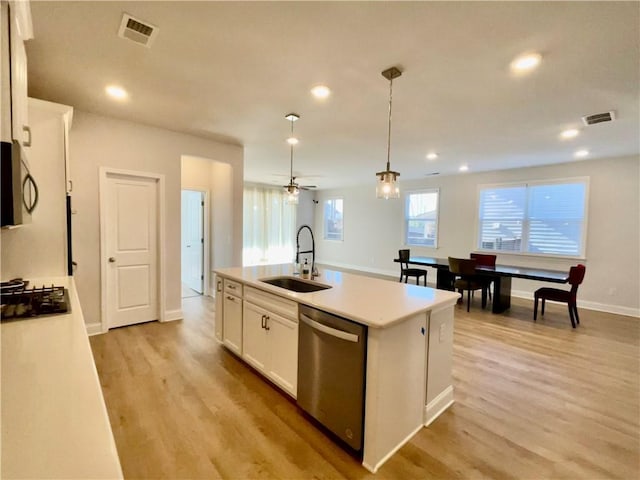 kitchen with pendant lighting, sink, stainless steel appliances, white cabinets, and a center island with sink