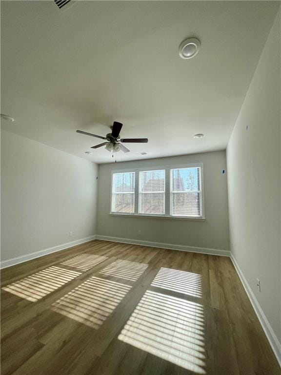 empty room featuring dark wood-type flooring and ceiling fan