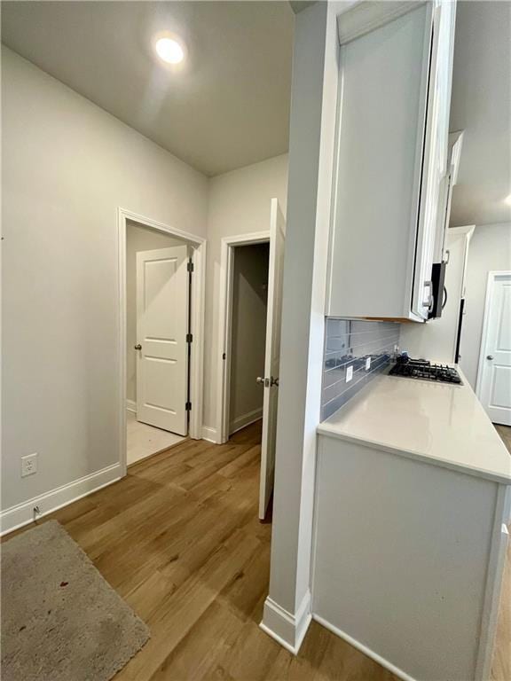 kitchen featuring gas cooktop, light wood-type flooring, decorative backsplash, and white cabinets