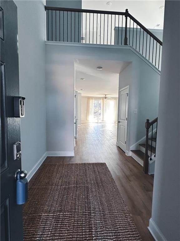 corridor with a towering ceiling and dark hardwood / wood-style floors