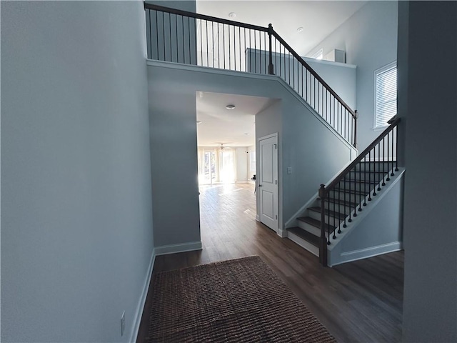 stairway featuring wood-type flooring and a high ceiling