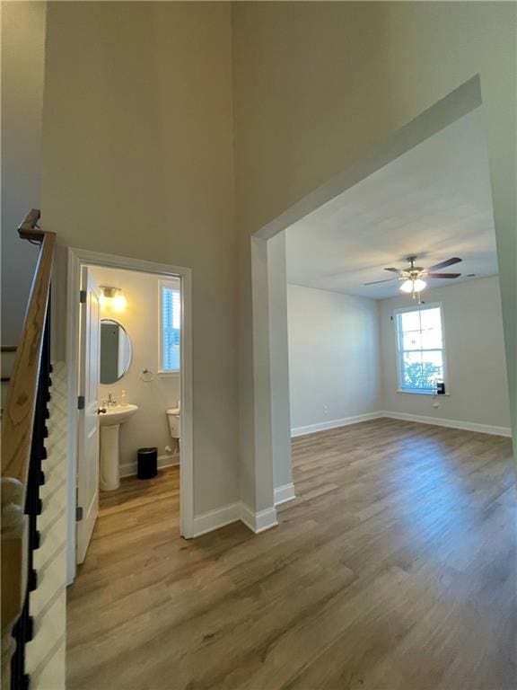 interior space with ceiling fan, a towering ceiling, sink, and light wood-type flooring