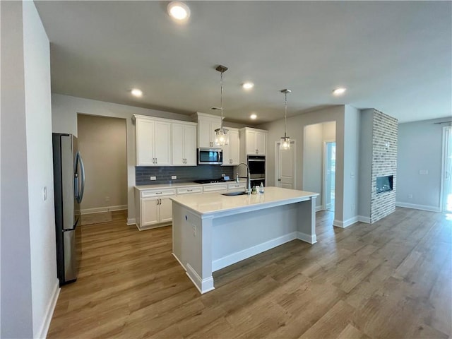 kitchen featuring pendant lighting, white cabinetry, a kitchen island with sink, and stainless steel appliances