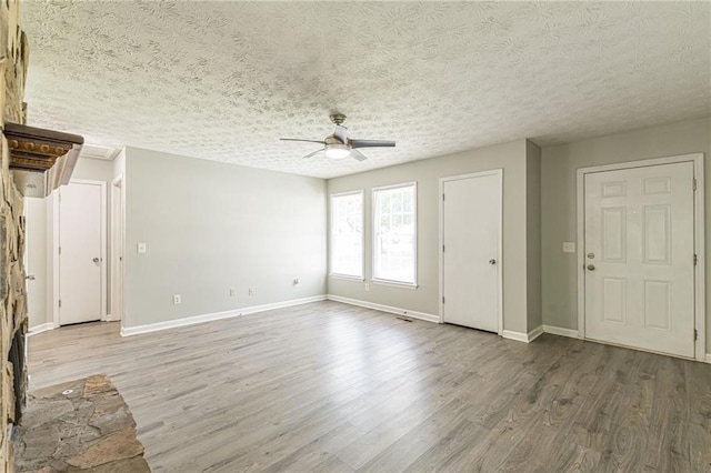 unfurnished living room featuring ceiling fan, wood-type flooring, and a textured ceiling