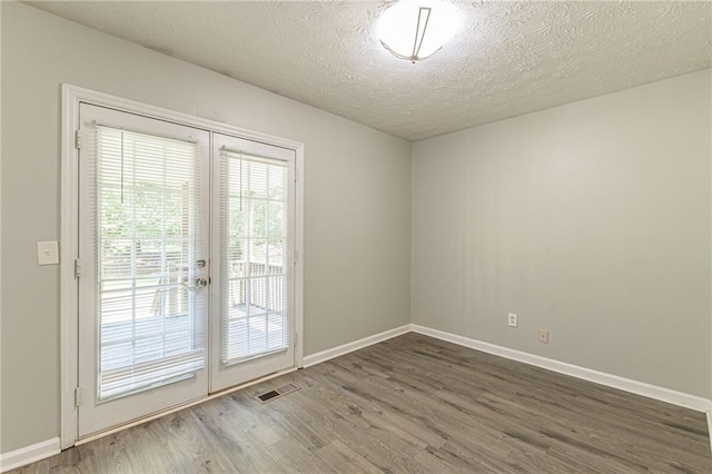 spare room featuring dark hardwood / wood-style flooring and a textured ceiling