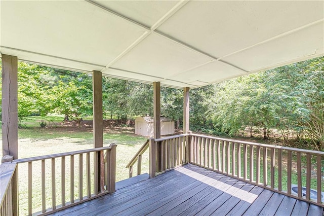 wooden terrace featuring a lawn and a shed