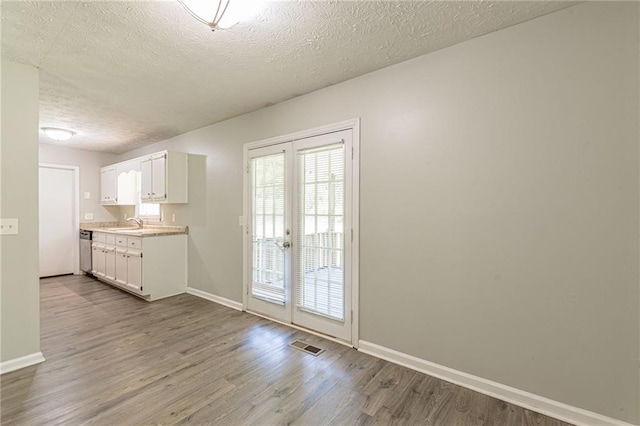 interior space with sink, french doors, a textured ceiling, and light hardwood / wood-style flooring