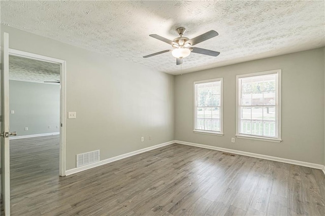 unfurnished room featuring ceiling fan, dark wood-type flooring, and a textured ceiling