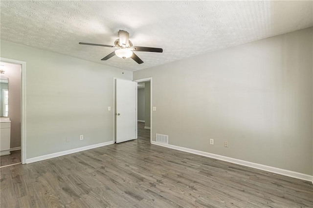 unfurnished bedroom with ceiling fan, dark hardwood / wood-style flooring, and a textured ceiling