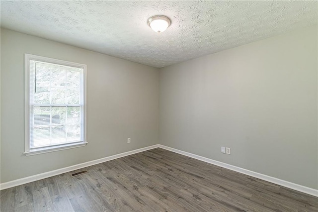 unfurnished room with dark hardwood / wood-style flooring and a textured ceiling