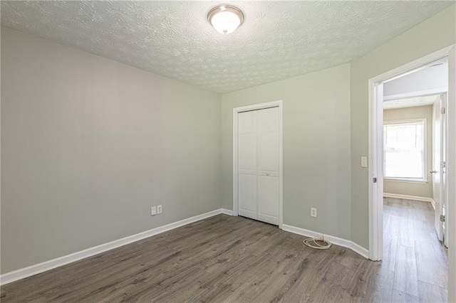 unfurnished bedroom featuring wood-type flooring, a textured ceiling, and a closet