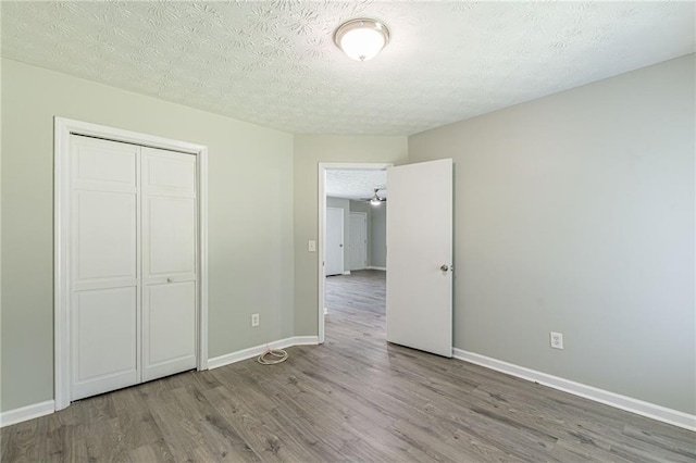 unfurnished bedroom featuring light hardwood / wood-style floors, a textured ceiling, and a closet