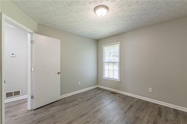 spare room with wood-type flooring and a textured ceiling