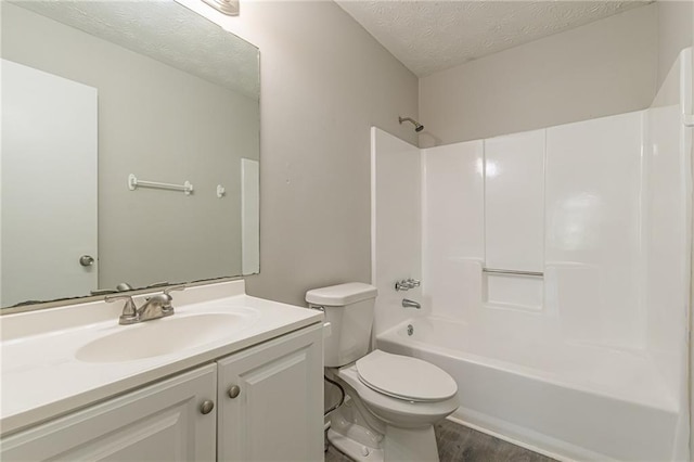 full bathroom with hardwood / wood-style floors, a textured ceiling, toilet, vanity, and bathtub / shower combination