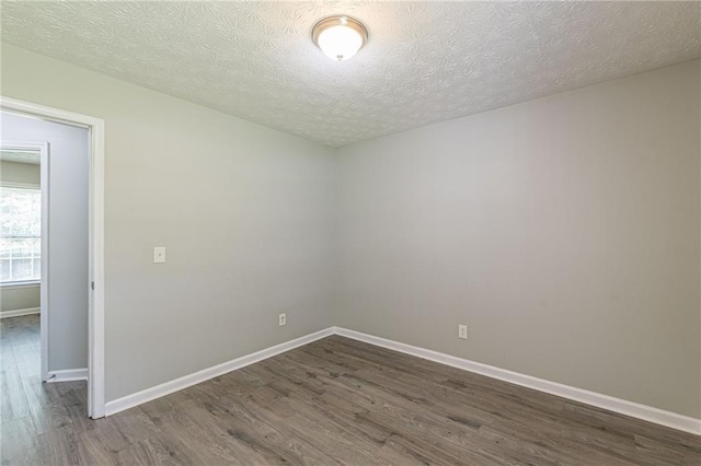 empty room featuring dark wood-type flooring and a textured ceiling