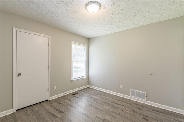 spare room with hardwood / wood-style flooring and a textured ceiling