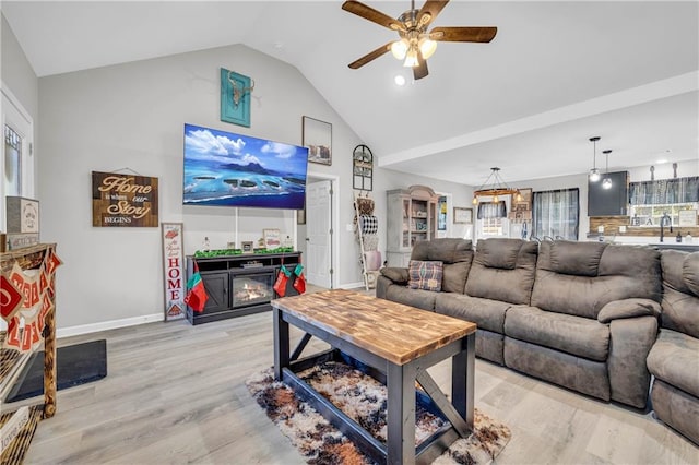 living room with a fireplace, ceiling fan, light wood-type flooring, and lofted ceiling