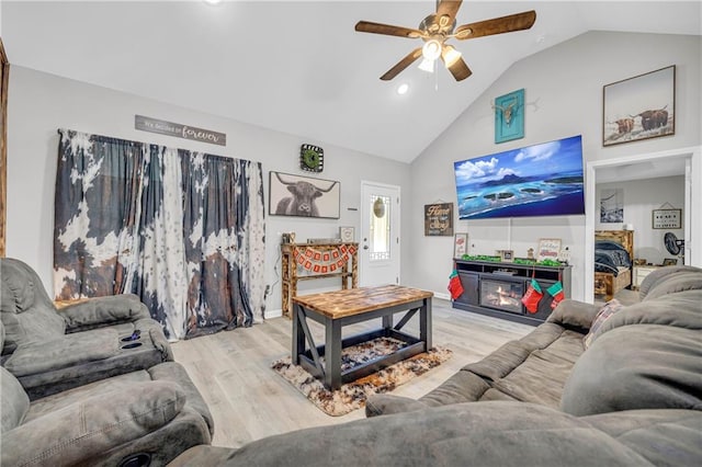 living room featuring light hardwood / wood-style flooring, lofted ceiling, and ceiling fan