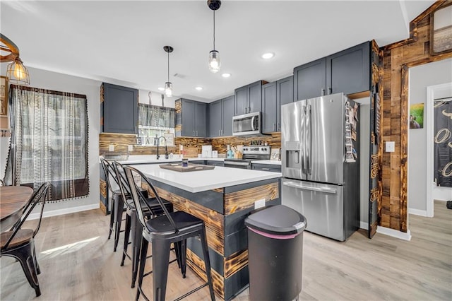 kitchen featuring hanging light fixtures, a healthy amount of sunlight, a kitchen island, and appliances with stainless steel finishes