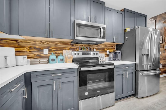 kitchen with gray cabinets, backsplash, and appliances with stainless steel finishes