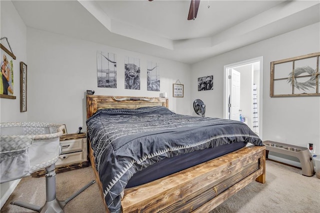 carpeted bedroom with ensuite bathroom, ceiling fan, and a raised ceiling