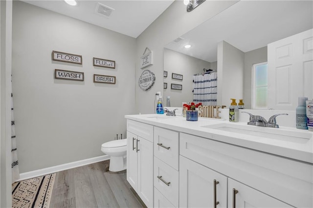 bathroom featuring hardwood / wood-style flooring, vanity, toilet, and curtained shower