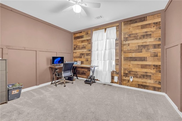 office area featuring wood walls, ceiling fan, and carpet