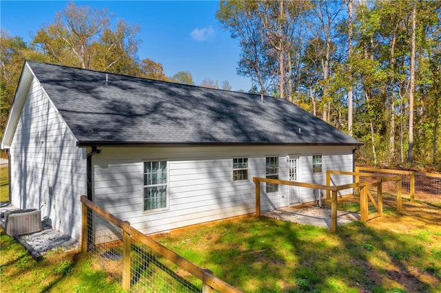 back of property with central air condition unit and a yard