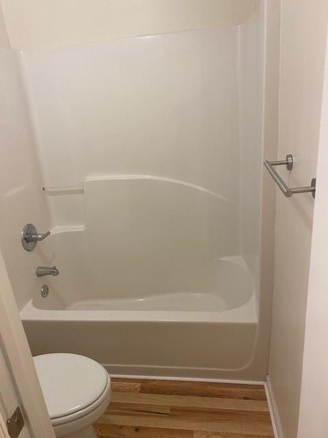 bathroom featuring shower / washtub combination, toilet, and hardwood / wood-style floors