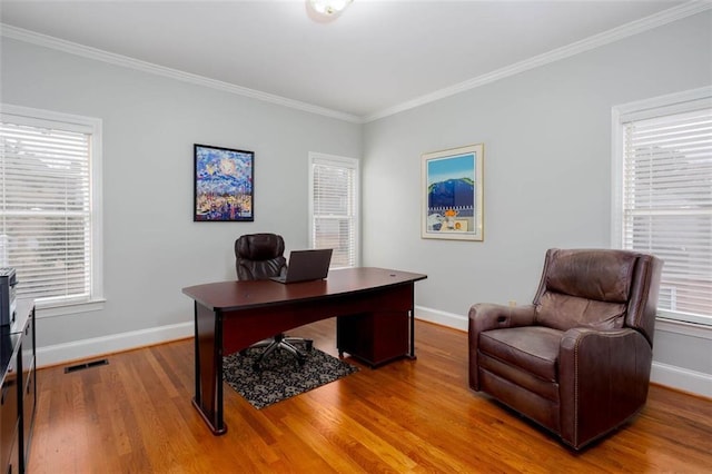 office featuring visible vents, crown molding, baseboards, and wood finished floors