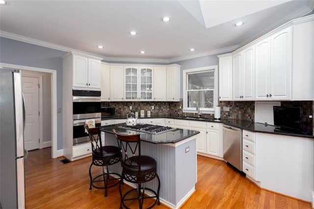 kitchen with a breakfast bar area, light wood finished floors, a sink, stainless steel appliances, and white cabinets