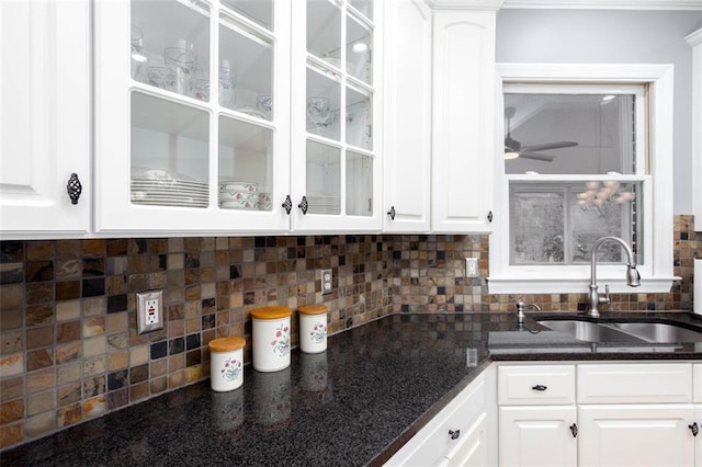 kitchen with tasteful backsplash, glass insert cabinets, and a sink