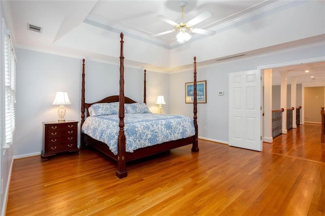 bedroom with baseboards, a raised ceiling, visible vents, and light wood finished floors