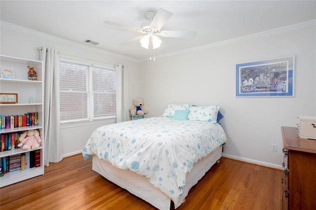 bedroom with wood finished floors, visible vents, and ornamental molding