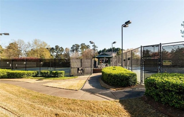 view of property's community with a tennis court, a gate, and fence