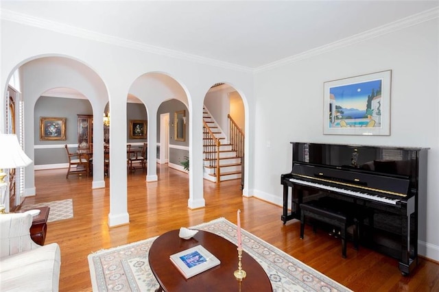 living area with baseboards, stairs, light wood-style floors, and ornamental molding