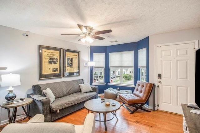 living room with ceiling fan, hardwood / wood-style flooring, and a textured ceiling