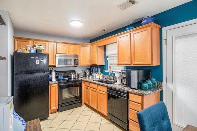 kitchen with light tile patterned floors, light stone countertops, sink, and black appliances