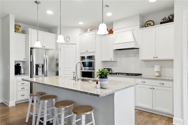 kitchen with stainless steel appliances, a sink, light wood-style floors, a breakfast bar area, and white cabinetry
