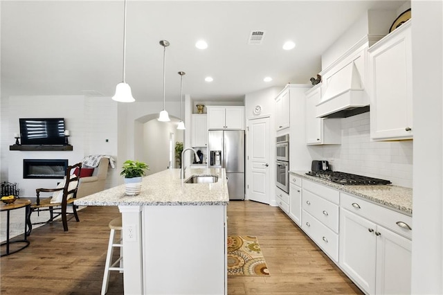 kitchen featuring a sink, appliances with stainless steel finishes, a kitchen bar, white cabinets, and arched walkways