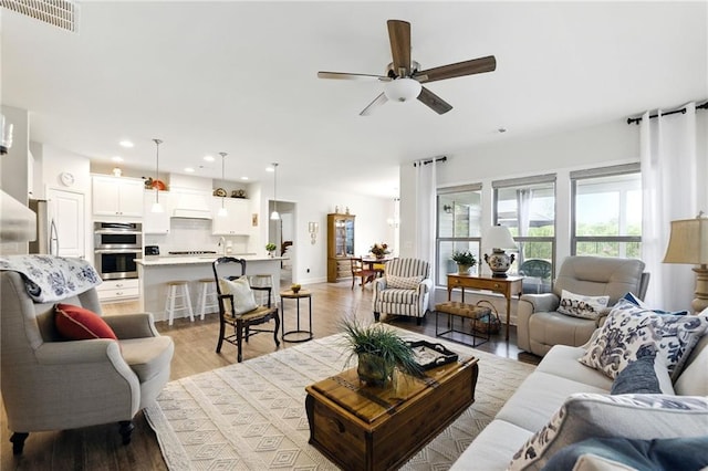 living room with a ceiling fan, recessed lighting, and light wood-style floors