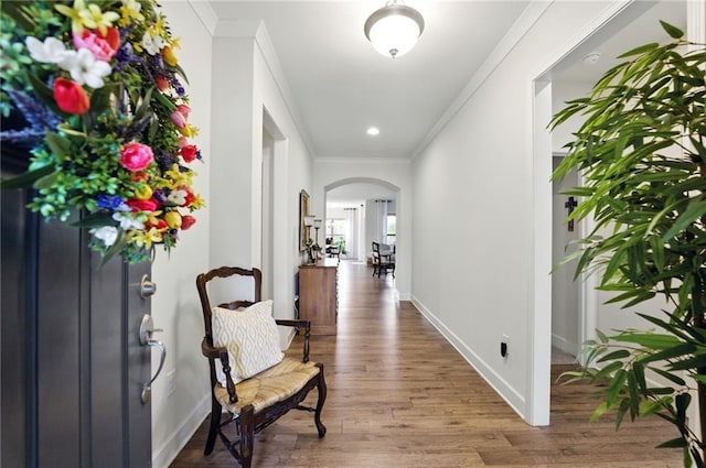 hall with arched walkways, crown molding, wood finished floors, baseboards, and recessed lighting