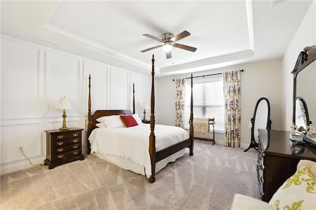 bedroom featuring a tray ceiling, light colored carpet, ceiling fan, and baseboards