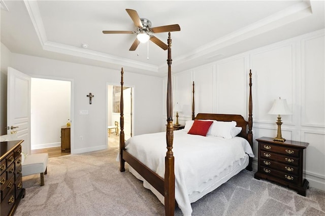bedroom with a raised ceiling, light colored carpet, ornamental molding, ceiling fan, and baseboards