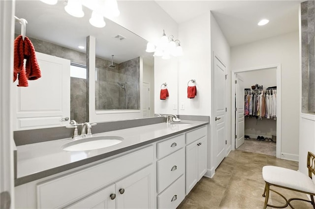 bathroom featuring a tile shower, double vanity, tile patterned flooring, and a walk in closet